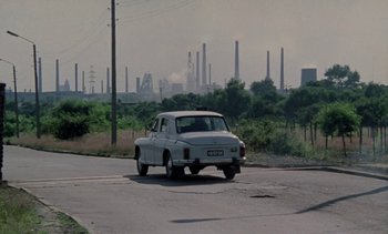 Movie still from “The Scar” (1976), directed by Krzysztof Kieslowski – An old car is driving down the street; Extreme Wide shot, Low angle