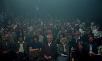 Movie still from “The Scar” (1976), directed by Krzysztof Kieslowski – A large group of people sitting in a room; Wide shot, High angle