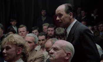 Movie still from “The Scar” (1976), directed by Krzysztof Kieslowski – A group of people sitting in a room; Medium shot, Over the shoulder angle