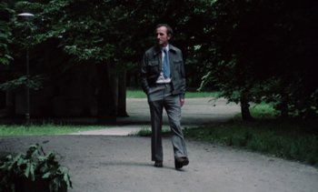 Movie still from “The Scar” (1976), directed by Krzysztof Kieslowski – A man walking down a path wearing a suit and tie; Wide shot, Low angle