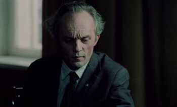 Movie still from “The Scar” (1976), directed by Krzysztof Kieslowski – An older man wearing a suit and tie; Close Up shot, Low angle