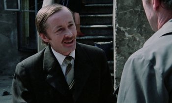 Movie still from “The Scar” (1976), directed by Krzysztof Kieslowski – A man wearing a suit and tie smiling; Close Up shot, Low angle