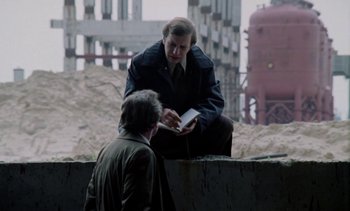 Movie still from “The Scar” (1976), directed by Krzysztof Kieslowski – A man is reading a book to another man; Medium shot, Over the shoulder angle