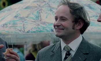 Movie still from “The Scar” (1976), directed by Krzysztof Kieslowski – A man in a suit and tie holding an umbrella; Close Up shot, Low angle