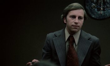 Movie still from “The Scar” (1976), directed by Krzysztof Kieslowski – A man in a suit and tie holding a pen; Close Up shot, Over the shoulder angle