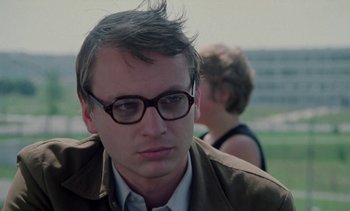 Movie still from “The Scar” (1976), directed by Krzysztof Kieslowski – A person wearing glasses and a jacket; Close Up shot, Low angle