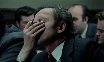 Movie still from “The Scar” (1976), directed by Krzysztof Kieslowski – A man in a suit and tie covering his face with his hand; Close Up shot, Over the shoulder angle