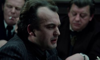 Movie still from “The Scar” (1976), directed by Krzysztof Kieslowski – A man in a suit and tie is sitting in front of another man in a suit and tie; Close Up shot, Over the shoulder angle