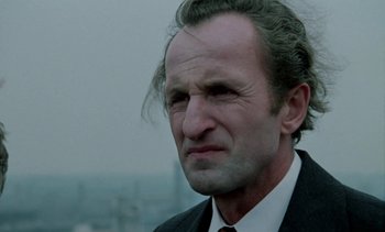 Movie still from “The Scar” (1976), directed by Krzysztof Kieslowski – A person wearing a suit and tie; Close Up shot, Low angle