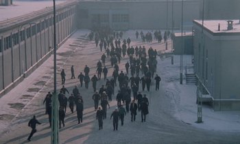 Movie still from “The Scar” (1976), directed by Krzysztof Kieslowski – A large group of people walking down a snowy street; Extreme Wide shot, High angle