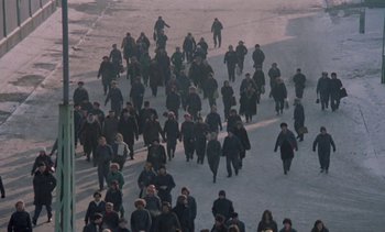 Movie still from “The Scar” (1976), directed by Krzysztof Kieslowski – A large group of people walking down a snow covered street; Extreme Wide shot, High angle