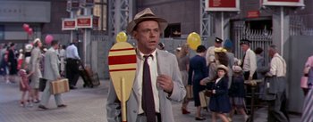 Movie still from “The Seven Year Itch” (1955), directed by Billy Wilder – A man in a suit and hat holding a paddle; Medium shot, Over the shoulder angle