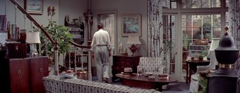 Movie still from “The Seven Year Itch” (1955), directed by Billy Wilder – A man walking through a living room in a house; Wide shot, High angle