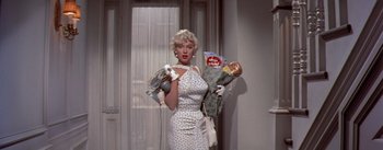 Movie still from “The Seven Year Itch” (1955), directed by Billy Wilder – A woman in a polka dot dress holding a bunch of food; Medium shot, Low angle