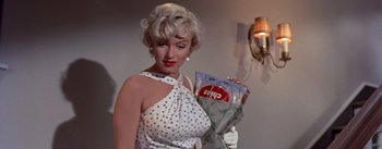 Movie still from “The Seven Year Itch” (1955), directed by Billy Wilder – A woman in a polka dot dress holding a bag of chips; Medium shot, Low angle