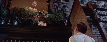 Movie still from “The Seven Year Itch” (1955), directed by Billy Wilder – A woman standing on top of a balcony with plants; Wide shot, Low angle