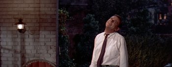 Movie still from “The Seven Year Itch” (1955), directed by Billy Wilder – A man wearing a tie standing in front of a building; Medium shot, Low angle