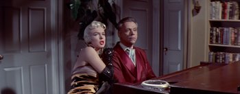 Movie still from “The Seven Year Itch” (1955), directed by Billy Wilder – A man and a woman sitting in front of a table; Medium shot, Low angle