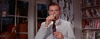 Movie still from “The Seven Year Itch” (1955), directed by Billy Wilder – A man in a suit and tie drinking a glass of wine; Close Up shot, High angle