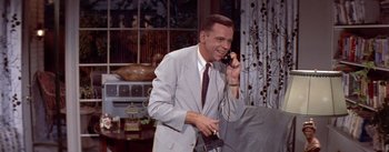 Movie still from “The Seven Year Itch” (1955), directed by Billy Wilder – An older man talking on a phone while wearing a suit and tie; Medium shot, High angle