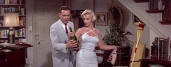 Movie still from “The Seven Year Itch” (1955), directed by Billy Wilder – A man and a woman holding a bottle of champagne; Medium shot, Low angle