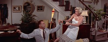 Movie still from “The Seven Year Itch” (1955), directed by Billy Wilder – A man and a woman holding hands in a living room; Medium shot, Overhead angle