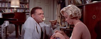 Movie still from “The Seven Year Itch” (1955), directed by Billy Wilder – A man and a woman are eating food and drinking soda; Medium shot, Low angle