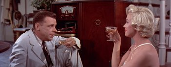 Movie still from “The Seven Year Itch” (1955), directed by Billy Wilder – A man and a woman holding wine glasses in their hands; Medium shot, High angle