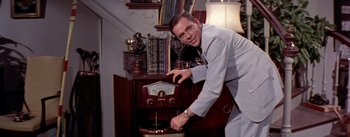 Movie still from “The Seven Year Itch” (1955), directed by Billy Wilder – A man standing in front of an old radio; Medium shot, High angle