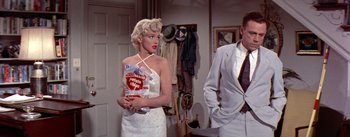 Movie still from “The Seven Year Itch” (1955), directed by Billy Wilder – A woman in a white dress holding a bag of potato chips; Medium shot, Over the shoulder angle