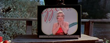 Movie still from “The Seven Year Itch” (1955), directed by Billy Wilder – A television with a picture of a woman covering her mouth; Close Up shot, Over the shoulder angle