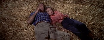 Movie still from “The Seven Year Itch” (1955), directed by Billy Wilder – A man and a woman laying in a pile of hay; Medium shot, Overhead angle