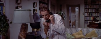 Movie still from “The Seven Year Itch” (1955), directed by Billy Wilder – A man in a white bathrobe is holding a phone; Close Up shot, High angle