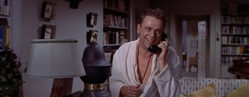 Movie still from “The Seven Year Itch” (1955), directed by Billy Wilder – A man talking on a phone while wearing a robe; Medium shot, Low angle