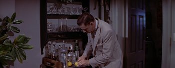 Movie still from “The Seven Year Itch” (1955), directed by Billy Wilder – A man in a suit and tie cutting a lemon; Medium shot, High angle