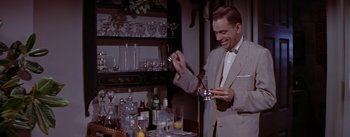 Movie still from “The Seven Year Itch” (1955), directed by Billy Wilder – A man in a suit holding a cup in his hand; Medium shot, High angle