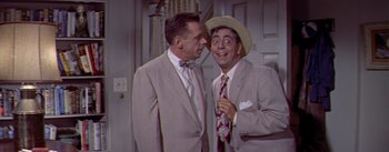 Movie still from “The Seven Year Itch” (1955), directed by Billy Wilder – Two men in suits and hats talking to each other; Medium shot, Over the shoulder angle