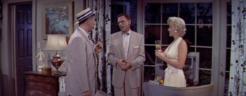 Movie still from “The Seven Year Itch” (1955), directed by Billy Wilder – A man and two women are talking to each other; Medium shot, Over the shoulder angle