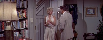 Movie still from “The Seven Year Itch” (1955), directed by Billy Wilder – A woman in a white dress talking to a man in a white suit; Medium shot, High angle