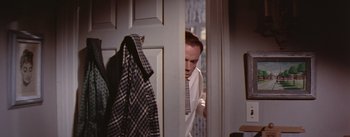Movie still from “The Seven Year Itch” (1955), directed by Billy Wilder – A man in a white dress shirt and tie looking through a door; Medium shot, Low angle