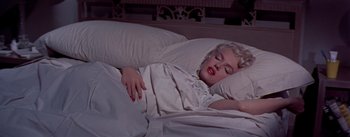 Movie still from “The Seven Year Itch” (1955), directed by Billy Wilder – A woman is sleeping in a bed with pillows and sheets; Medium shot, Overhead angle