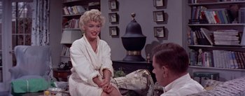 Movie still from “The Seven Year Itch” (1955), directed by Billy Wilder – A woman sitting on a chair in front of a man; Medium shot, Over the shoulder angle