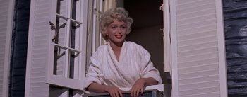 Movie still from “The Seven Year Itch” (1955), directed by Billy Wilder – A woman in a white bathrobe standing in a window; Medium shot, Low angle
