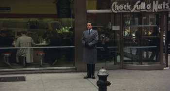 Movie still from “The Seven-Ups” (1973), directed by Philip D'Antoni – A man standing in front of a fire hydrant on the sidewalk; Wide shot, Over the shoulder angle
