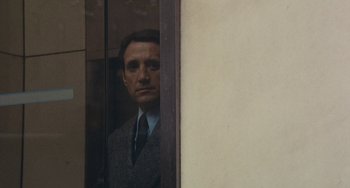 Movie still from “The Seven-Ups” (1973), directed by Philip D'Antoni – A man wearing a suit and tie looking out of a window; Close Up shot, Over the shoulder angle