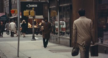 Movie still from “The Seven-Ups” (1973), directed by Philip D'Antoni – A man walking down the street in a brown suit; Wide shot, Over the shoulder angle