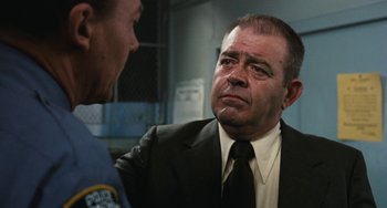 Movie still from “The Seven-Ups” (1973), directed by Philip D'Antoni – A man in a suit and tie talking to a police officer; Close Up shot, Low angle