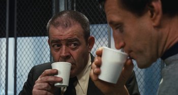 Movie still from “The Seven-Ups” (1973), directed by Philip D'Antoni – Two men are drinking from white paper cups; Close Up shot, Over the shoulder angle