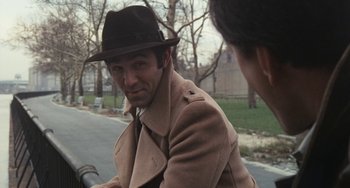 Movie still from “The Seven-Ups” (1973), directed by Philip D'Antoni – A man wearing a hat and a coat on a bicycle; Close Up shot, Over the shoulder angle