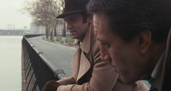 Movie still from “The Seven-Ups” (1973), directed by Philip D'Antoni – Two men in coats and hats looking over a railing; Close Up shot, Over the shoulder angle